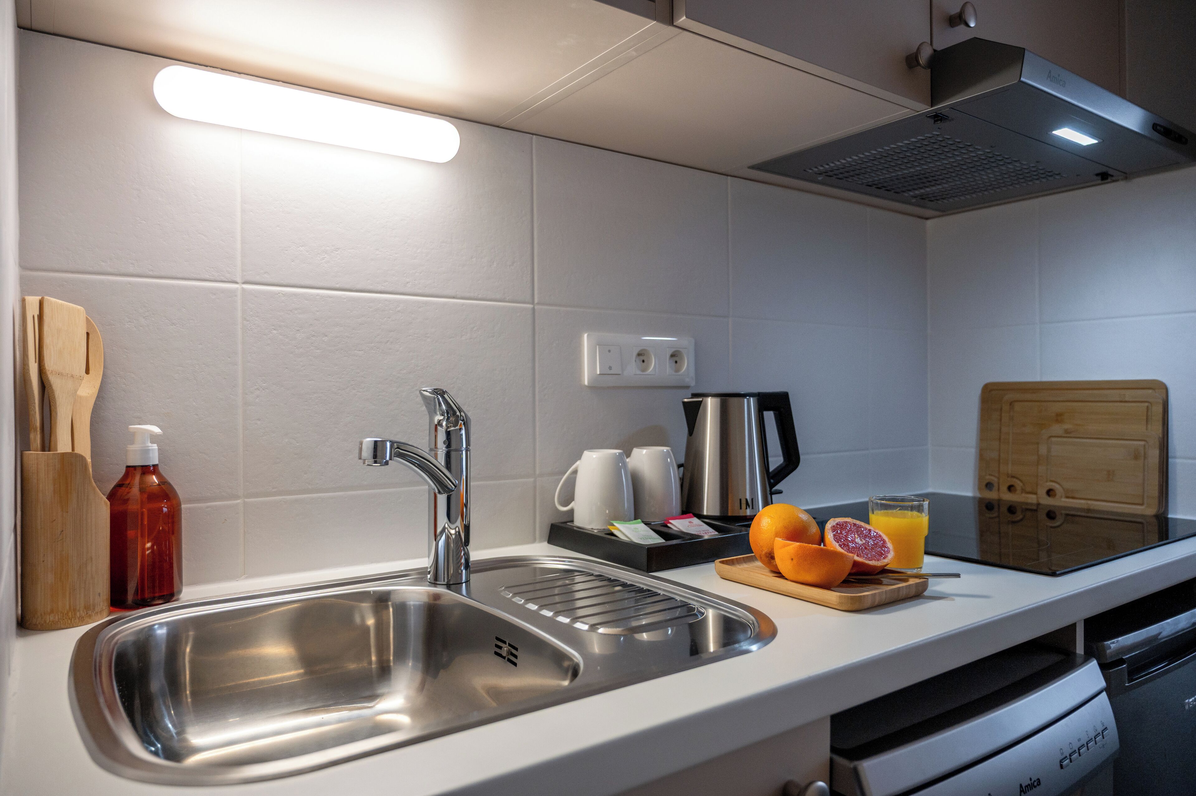 A modern kitchen with a stainless steel sink, a coffee maker, and a cutting board with fruit.