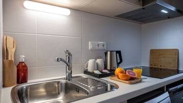 A modern kitchen with a stainless steel sink, a coffee maker, and a cutting board with fruit.