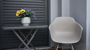 A white chair next to a table with a vase of flowers. - Nafpaktos Cozy Nest Homely Vibes Near the Beach (Nafpaktos)