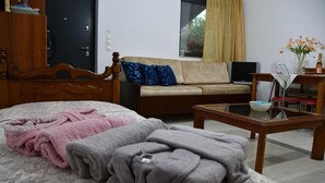 A bedroom with a bed, a wooden dresser, a sofa, a TV, and a small table with a vase of flowers. - Nafpaktos Cozy Nest Homely Vibes Near the Beach (Nafpaktos)