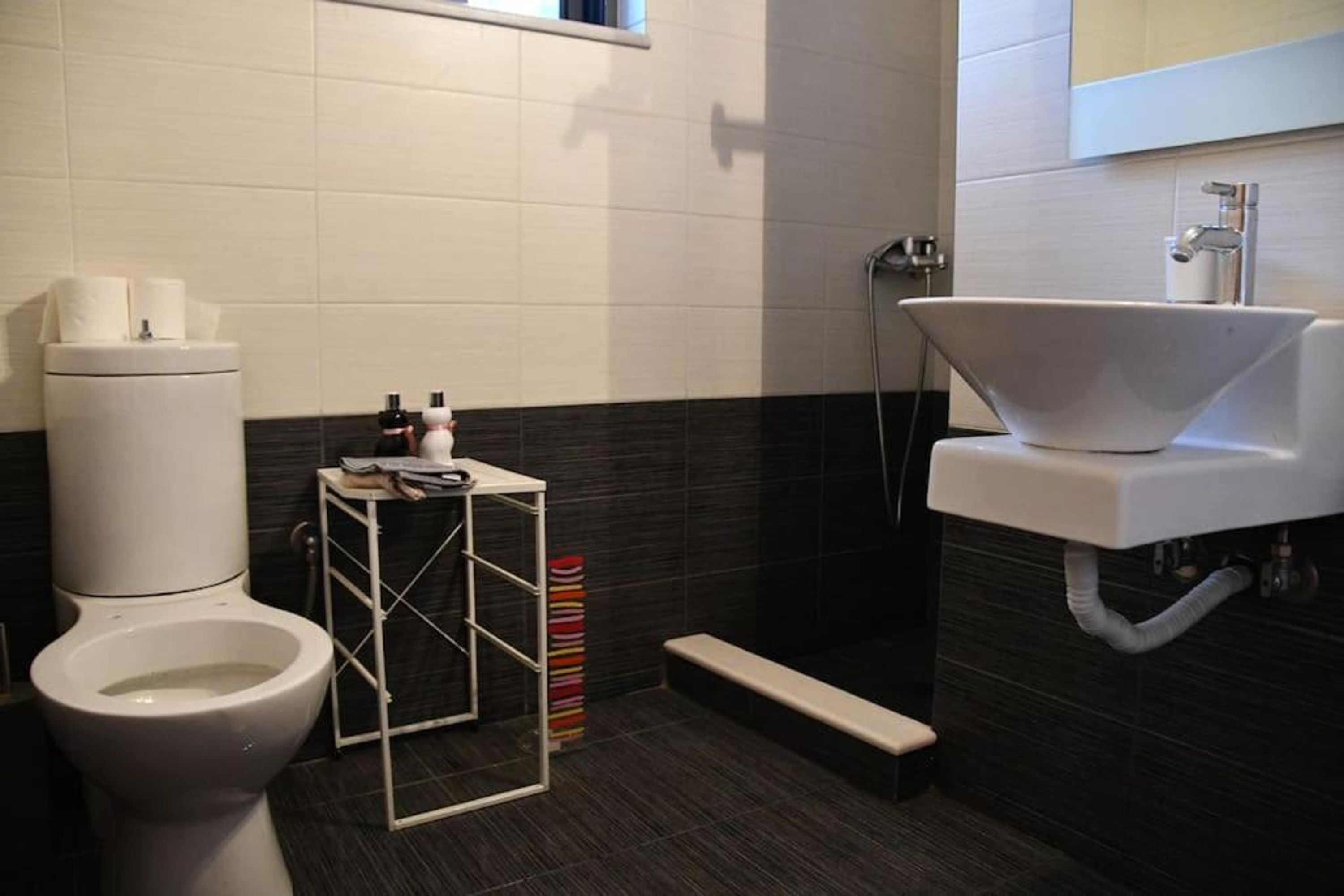 A modern bathroom with a toilet, a white sink, and a shower.