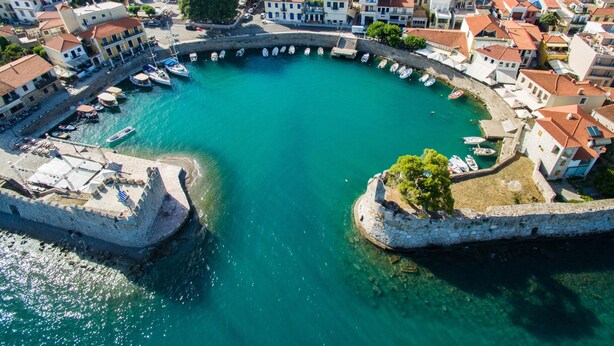 An aerial view of a coastal town with a central harbor, surrounded by closely packed buildings with red-tiled roofs, and a fortified structure on the right. - Nafpaktos Cozy Nest Homely Vibes Near the Beach (Nafpaktos)