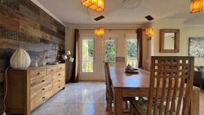 Un comedor con mesa y sillas de madera, un mueble de madera con cajones, y una pared con textura decorativa.