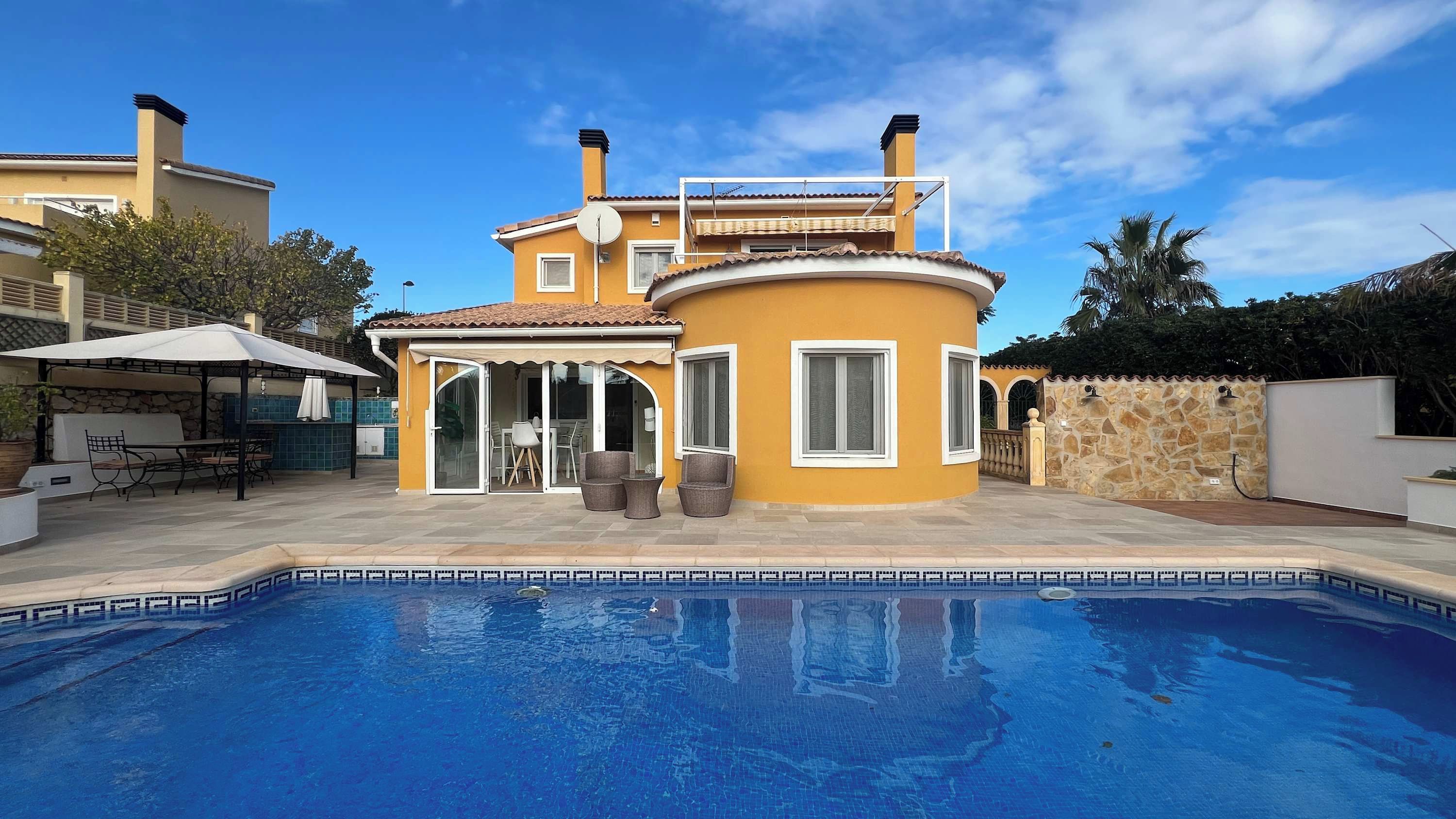 Uma casa de dois andares com uma piscina em frente.