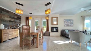 Un salón amplio con comedor, chimenea y un ventanal que proporciona luz natural.