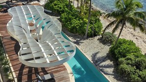 Une piscine au design original, entourée de palmiers et offrant une vue sur la plage.