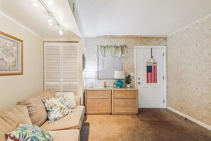 En hyggelig stue med en sofa, et sofabord med en lampe og en dør med et amerikansk flag.