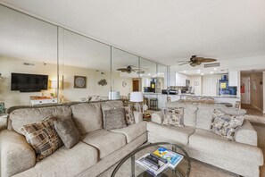 Una sala de estar con un sofá modular, una mesa de centro y un televisor.