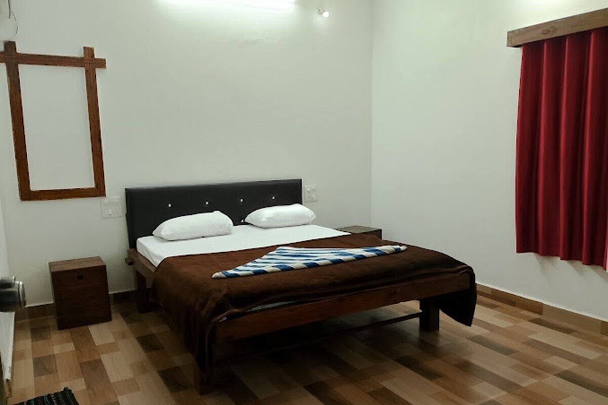 Une chambre à coucher avec un lit, une table de chevet, un plancher en bois et un rideau rouge.