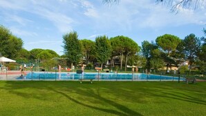 En swimmingpool omgiven av en gräsyta med träd i bakgrunden.