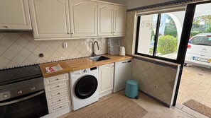 A compact kitchen with a washing machine, a sink, and cabinets.