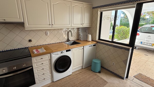A compact kitchen with a washing machine, a sink, and cabinets.