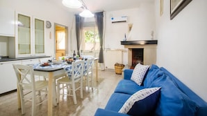 A compact living space with a dining area, a blue sofa, a fireplace, and a kitchen. - Villa Porto Cesareo Con Parcheggio (Porto Cesareo)