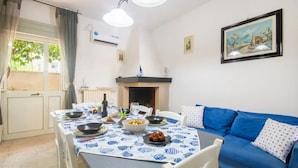 A dining area with a table set for four, a blue sofa, a fireplace, and a framed picture on the wall. - Villa Porto Cesareo Con Parcheggio (Porto Cesareo)