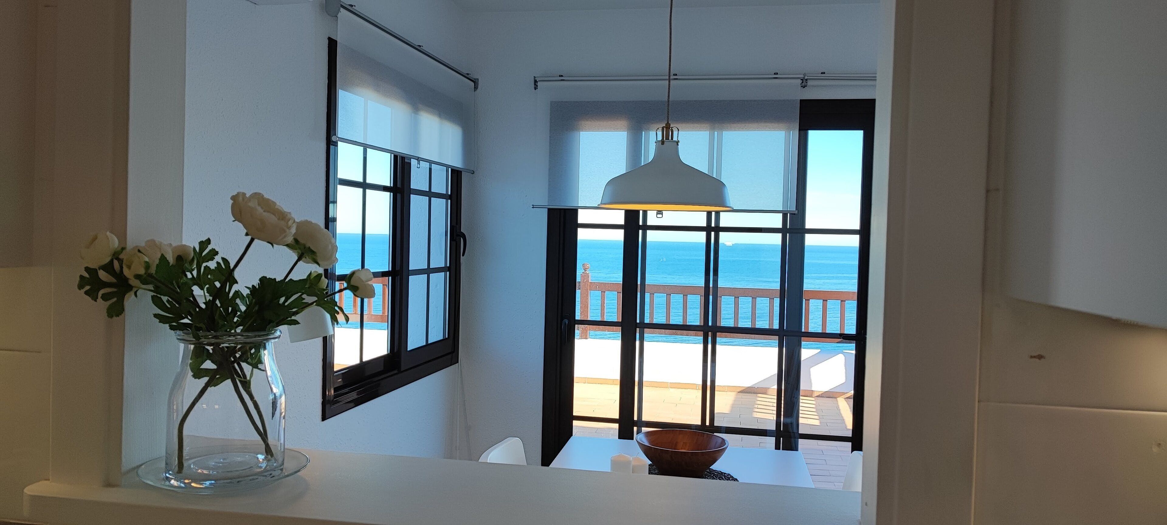 Bagno con un'ampia finestra vista piscina e mare.