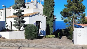 A white building with a tiled roof, a small garden, and a view of the sea. - Apartment with sea views and private pool (Llançà)
