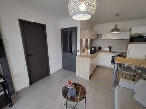 A modern kitchen with white cabinets, a dining area with a table and chairs, and a small seating area with a sofa.