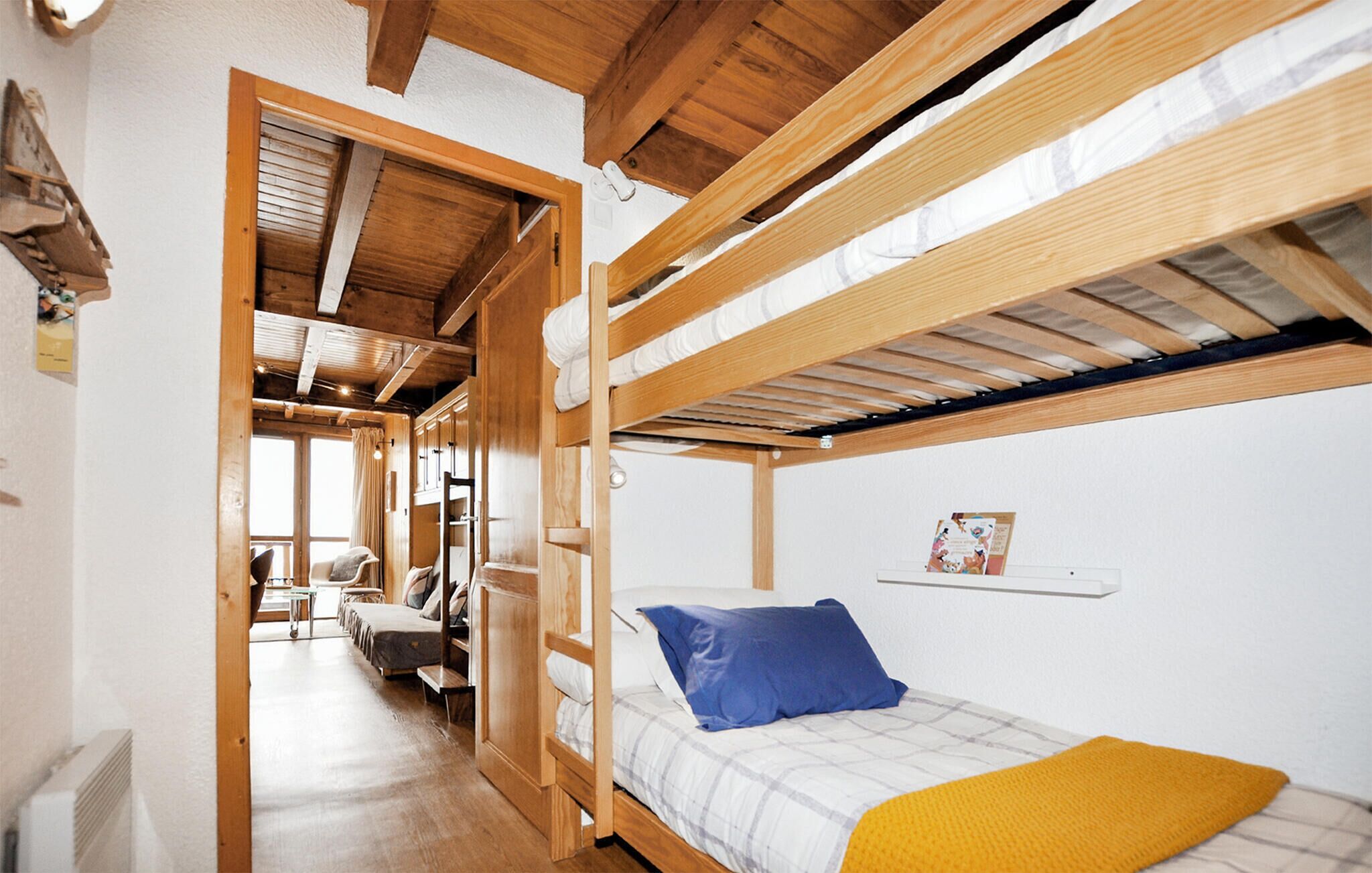 A bunk bed room with a wooden ceiling, a small table, and a chair.