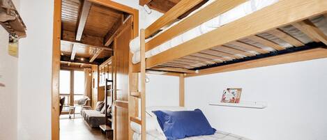 A bunk bed room with a wooden ceiling, a small table, and a chair.