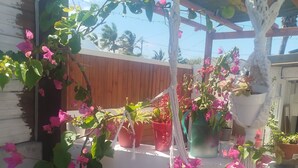 A balcony with potted plants and flowers, wooden railing, and a view of the sky. - Le lotus rental in terre sainte, 2 minutes from the beach (Saint-Pierre)