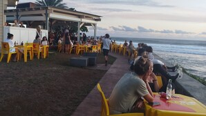 An outdoor dining area with yellow chairs and tables, overlooking the ocean. - Le lotus rental in terre sainte, 2 minutes from the beach (Saint-Pierre)