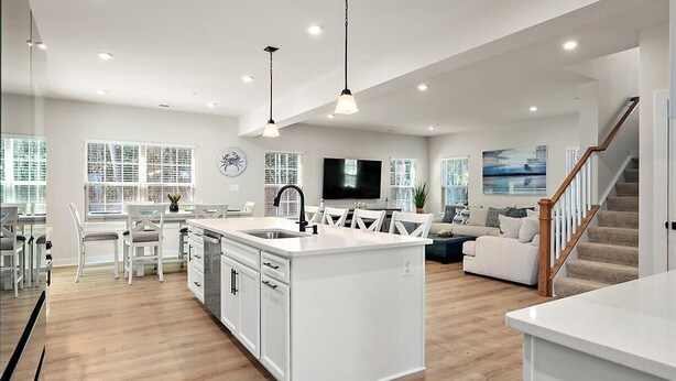 Cocina moderna con armarios blancos, una isla central e iluminación colgante.