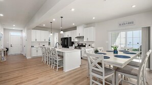 Una cocina moderna con armarios blancos, una isla central e iluminación colgante.