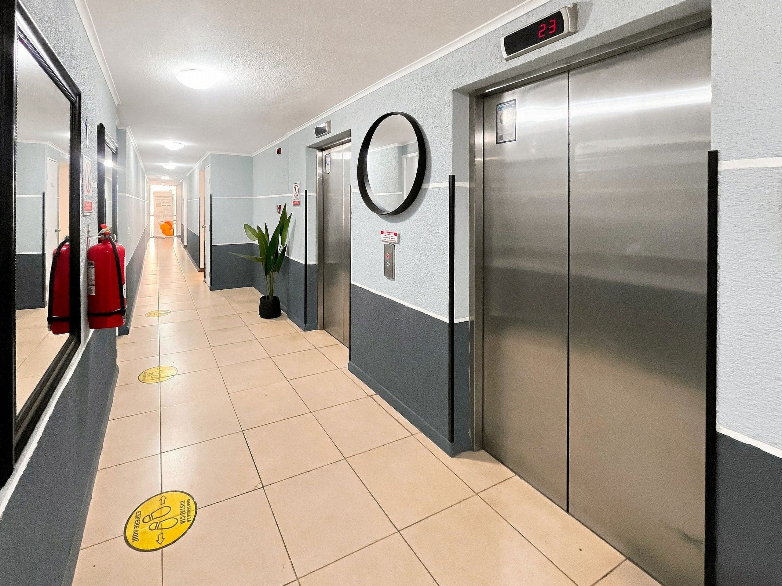 En gang med brandslukker, en plante og elevator.