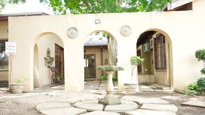 Un patio con escalones de piedra, arcos y un cartel de recepción que indica una piscina.