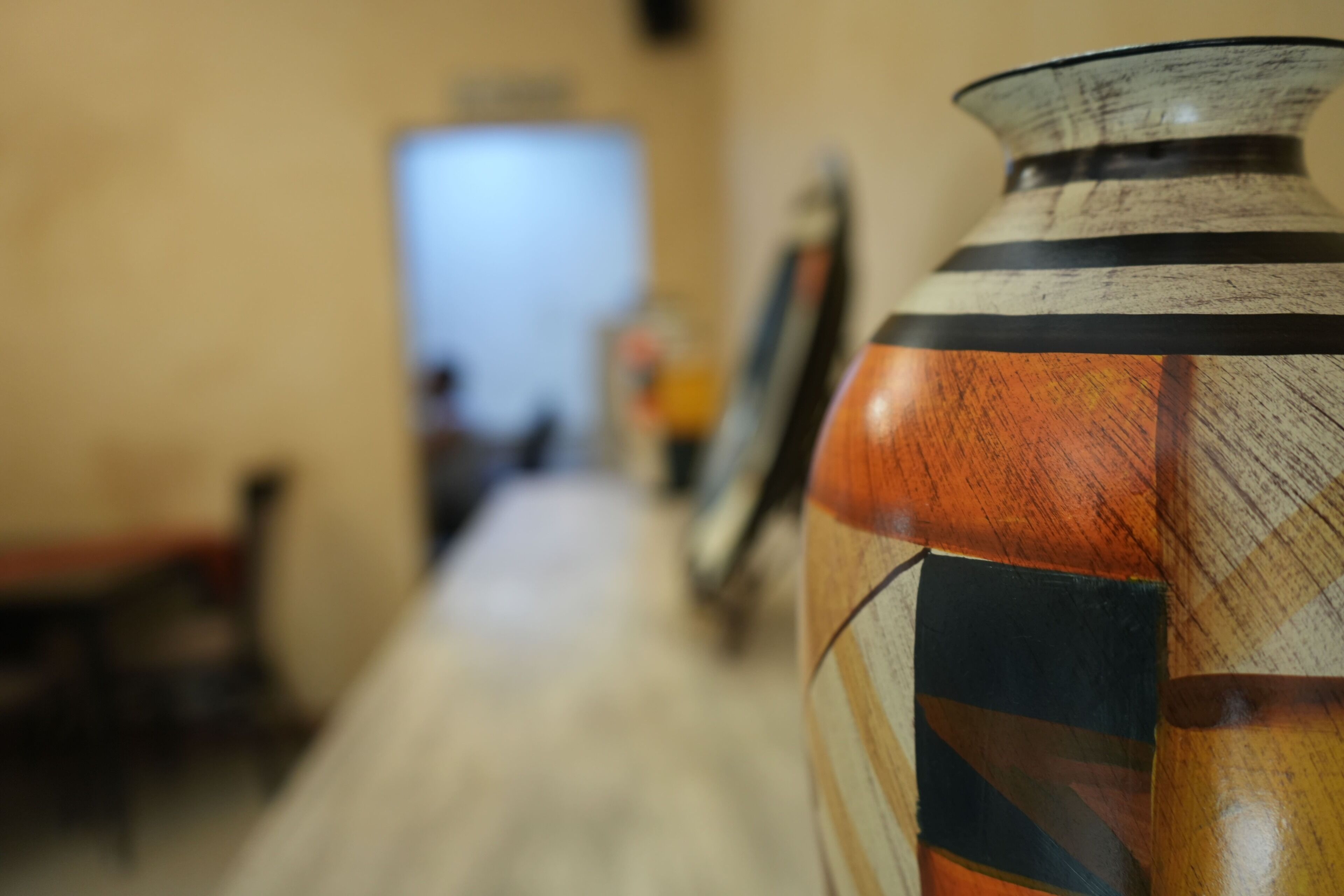 Un gros plan d’un vase décoratif orné de motifs géométriques, posé sur une surface en bois.