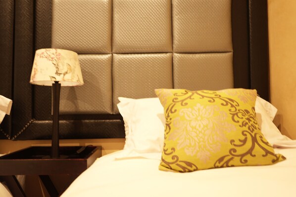 Une chambre d’hôtel avec une tête de lit capitonnée, une lampe de chevet et un coussin décoratif.