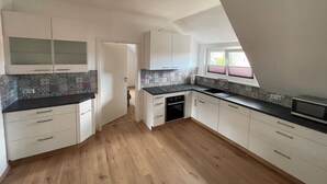 Eine moderne Küche mit weißen Schränken, einer schwarzen Arbeitsplatte und einer gemusterten Spritzschutzwand.