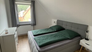 Ein Schlafzimmer mit Bett, Schreibtisch und einem Vorhangfenster.