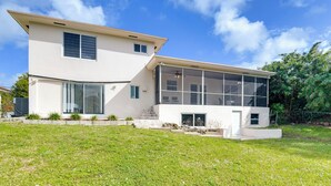 A modern two-story house with a large glass extension, a stone staircase, and a well-maintained lawn. - 8 Mi to Wynwood: Waterfront Retreat w/ Lanai (North Miami)