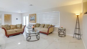 A spacious living room with a beige sofa, a glass coffee table, and a floor lamp. - 8 Mi to Wynwood: Waterfront Retreat w/ Lanai (North Miami)