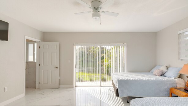 A bedroom with two beds, a ceiling fan, and a sliding glass door to a balcony. - 8 Mi to Wynwood: Waterfront Retreat w/ Lanai (North Miami)