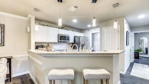 A kitchen with white cabinets, a stainless steel refrigerator, a microwave, and a sink. There are two bar stools with cushioned seats. - San Antonio Condo: 10 Mi to Dtwn! (San Antonio)