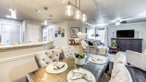 A modern living room with a large TV, comfortable seating, and a dining area with a wooden table and chairs. - San Antonio Condo: 10 Mi to Dtwn! (San Antonio)