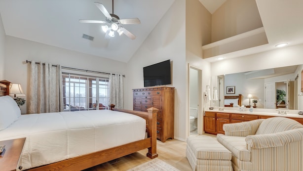 A spacious bedroom with a large bed, wooden dresser, and a TV mounted on the wall. - Walk to Branson Strip: Inviting Condo! (Branson)