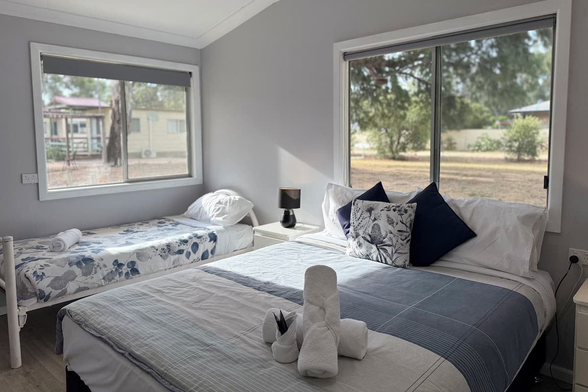 Een slaapkamer met twee bedden, een raam en uitzicht op de omgeving.