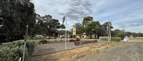 A sign for Hay Caravan Park with a flagpole and surrounding vegetation.