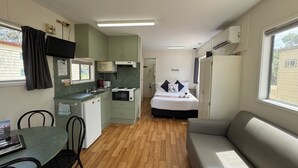 Habitació compacta amb petita cuina, un llit, un sofà i zona de menjador.