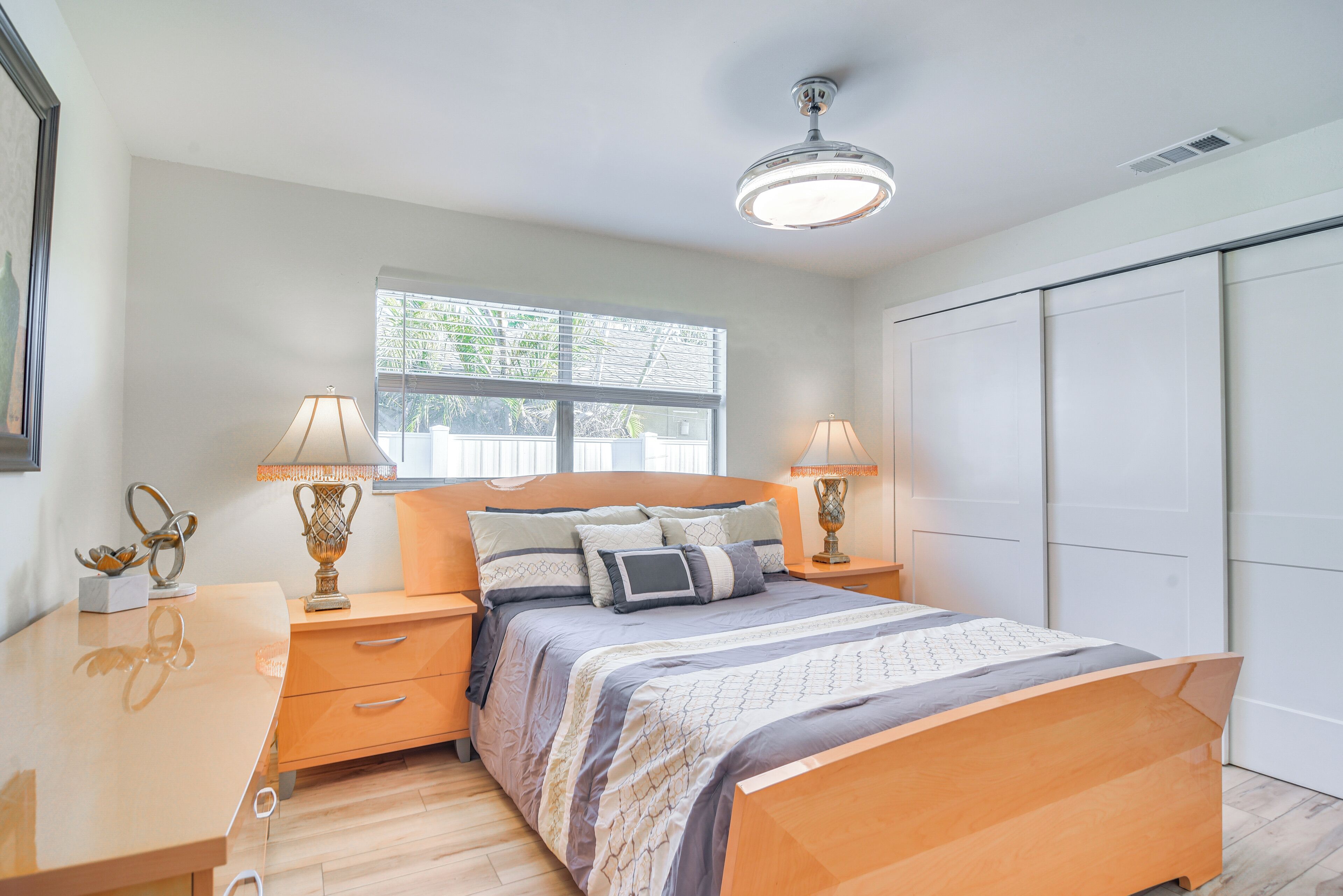 A bedroom with a bed, bedside tables, lamps, a window, and a wardrobe.