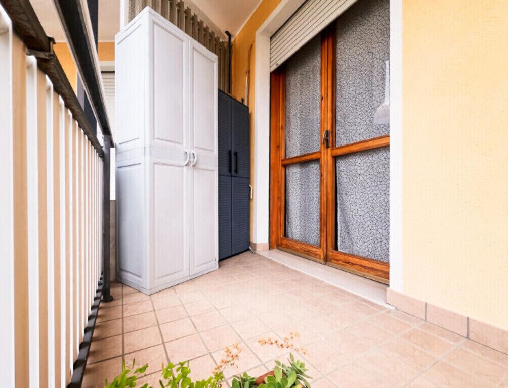 Un pasillo con un armario blanco, un mueble oscuro y un ventanal con vidrio esmerilado.