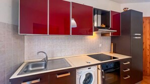 Une cuisine compacte équipée d’un lave-linge intégré, d’un évier et d’un four à micro-ondes.