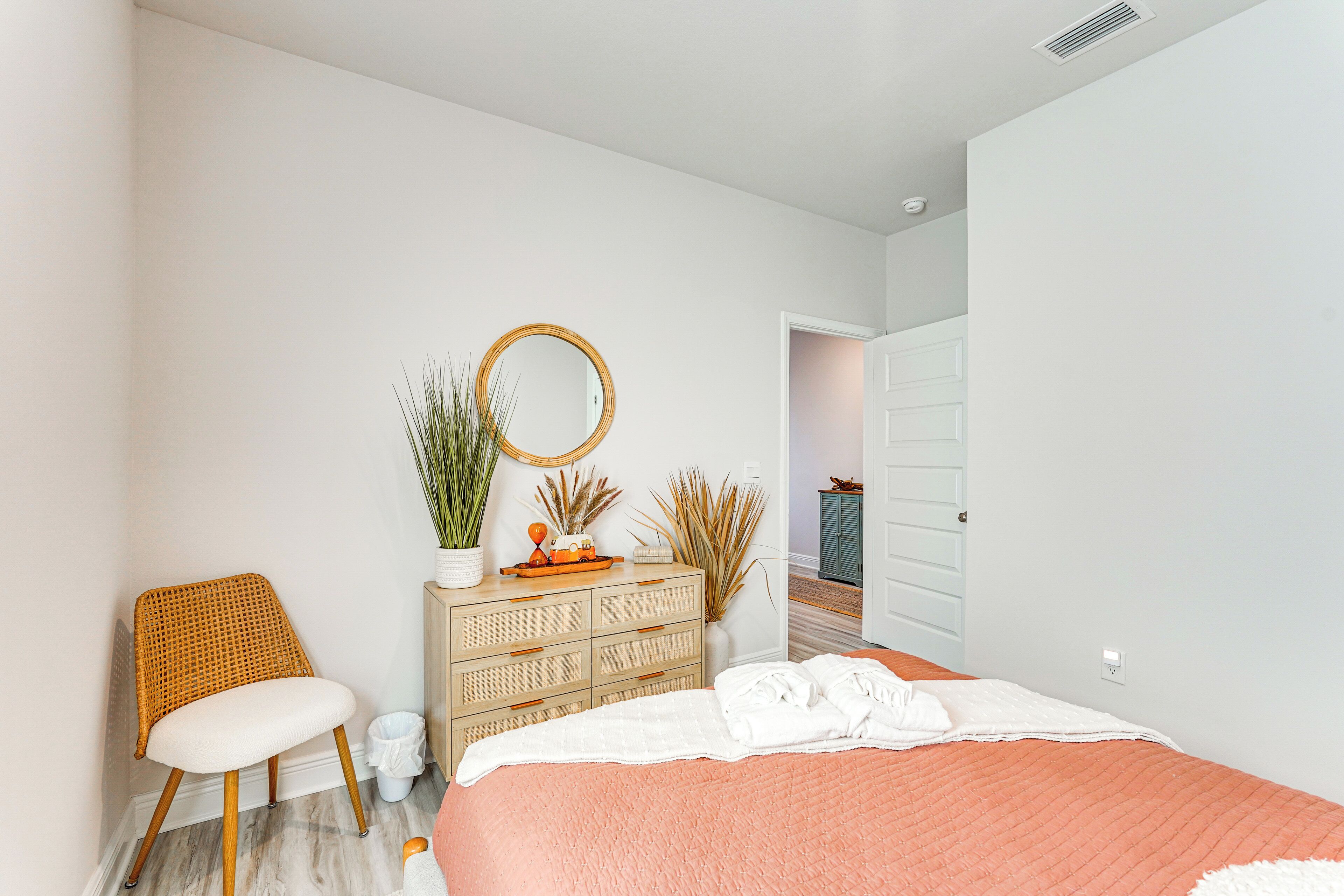 A bedroom with a bed, a dresser, a chair, and a mirror.