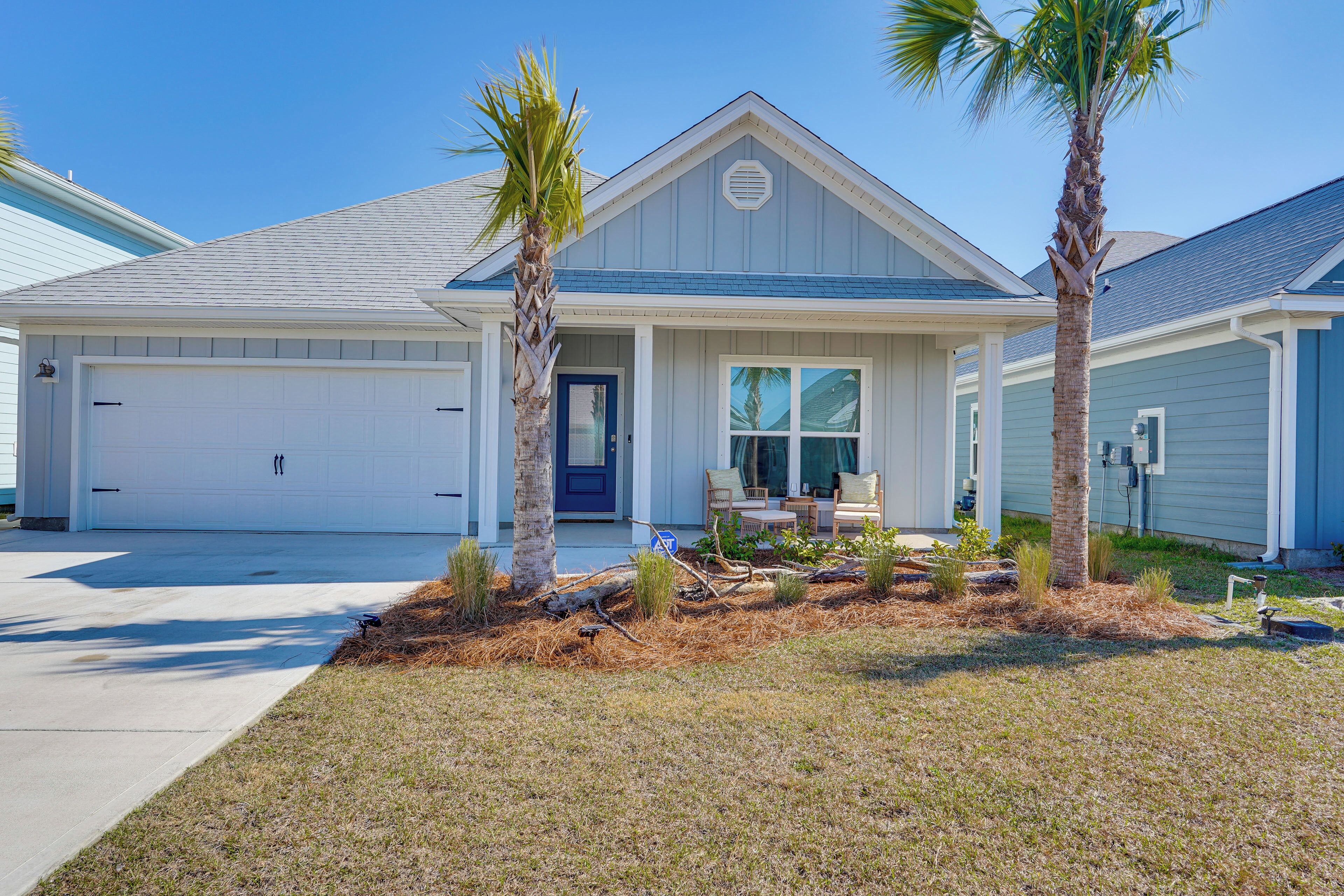A single-story house with a garage, two palm trees, and a well-maintained lawn.