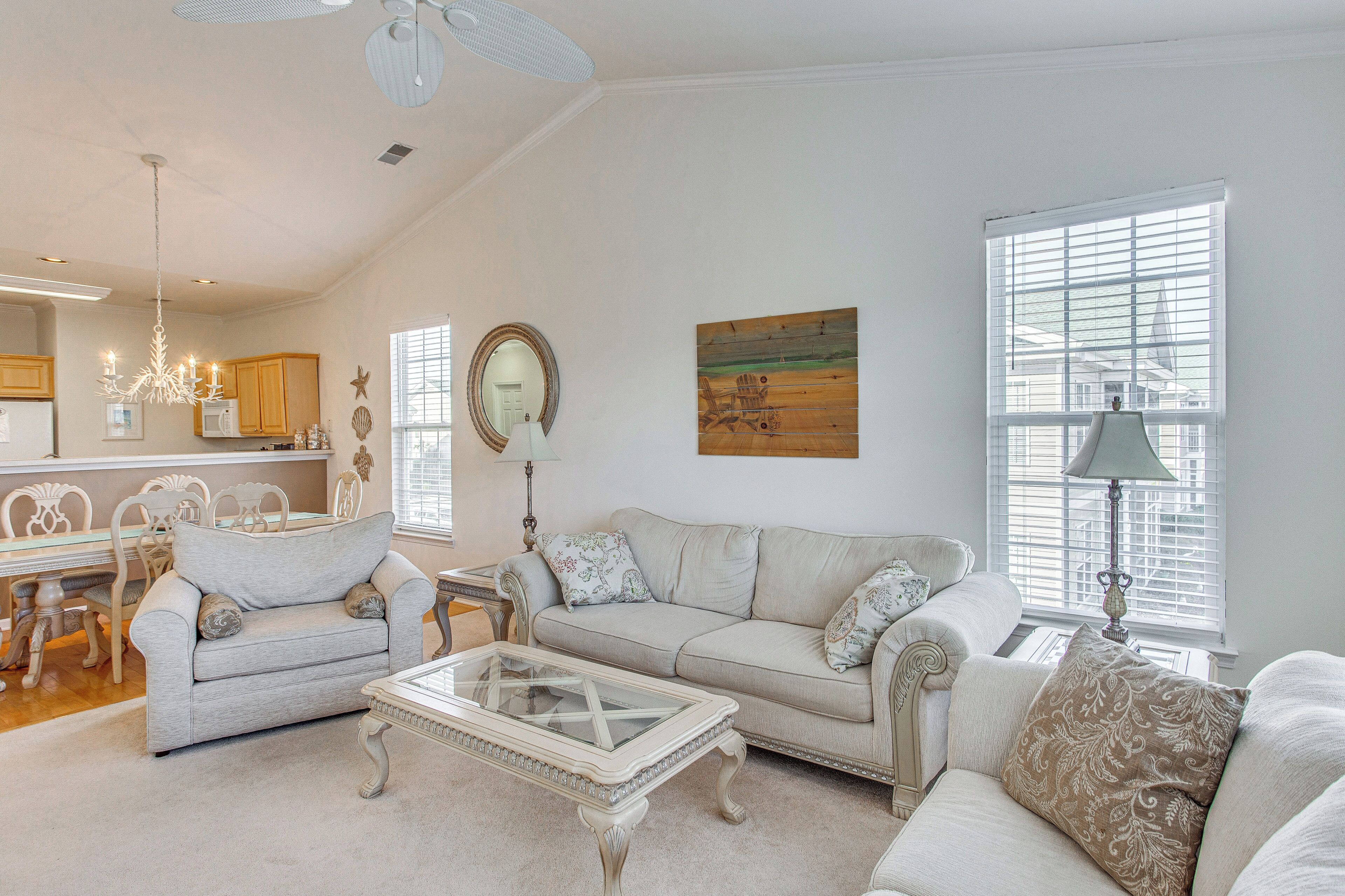 A living room with a sofa, coffee table, and a dining area with chairs and a table.