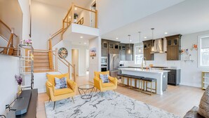 A spacious living area with a high ceiling, a staircase, and a kitchen with modern appliances. - 10 Mi to Morristown: Stylish Home Near Trails! (Rockaway)
