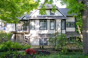 A two-story house with a covered porch, a small deck, and a garden with various plants and flowers.